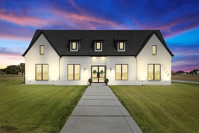 back house at dusk with french doors and a yard