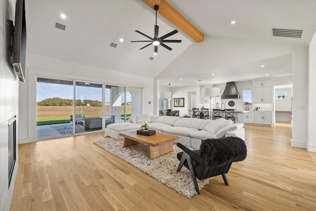 living room with beamed ceiling, ceiling fan, high vaulted ceiling, and light hardwood / wood-style floors