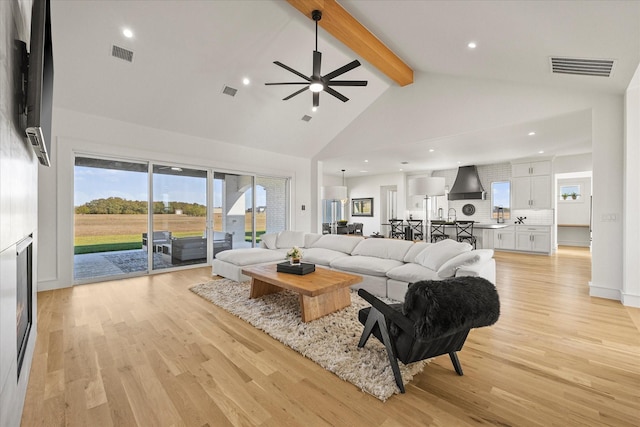 living room featuring visible vents, light wood-style flooring, and beam ceiling