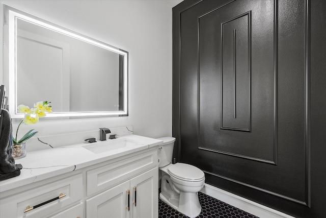 half bath featuring tile patterned floors, vanity, and toilet