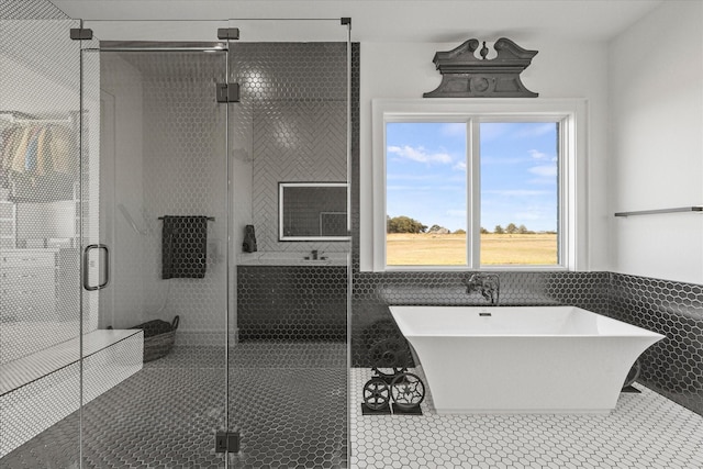 full bathroom with tile patterned floors, a freestanding bath, a stall shower, and tile walls