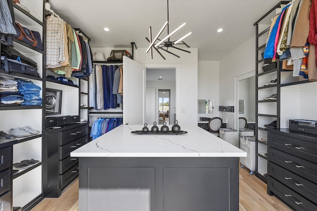 spacious closet with an inviting chandelier and light wood-style flooring