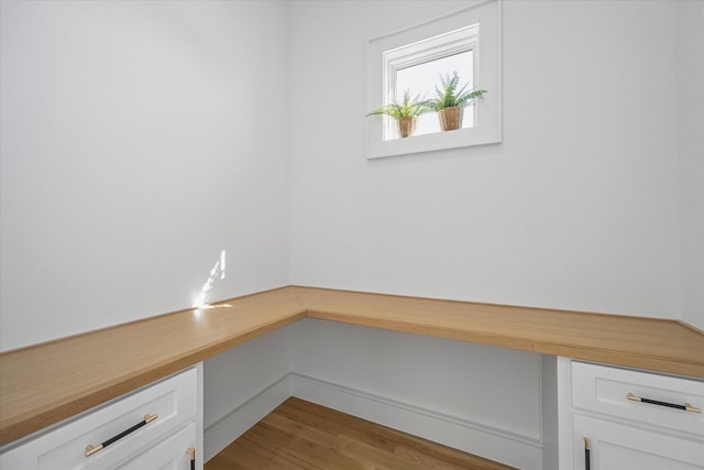 unfurnished office with baseboards, light wood finished floors, and built in study area