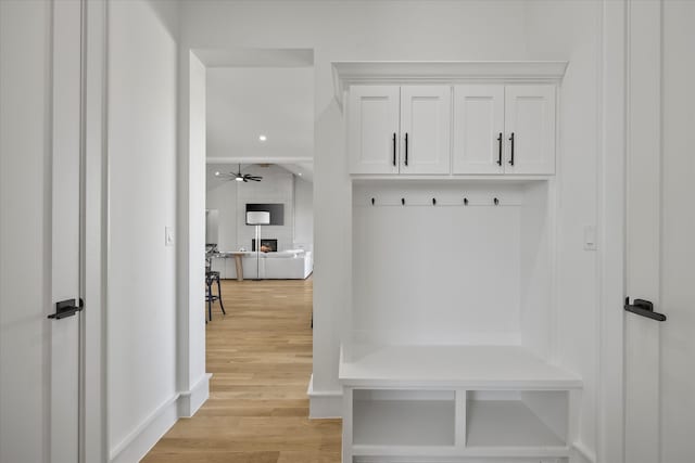 mudroom featuring ceiling fan, a fireplace, and light hardwood / wood-style flooring