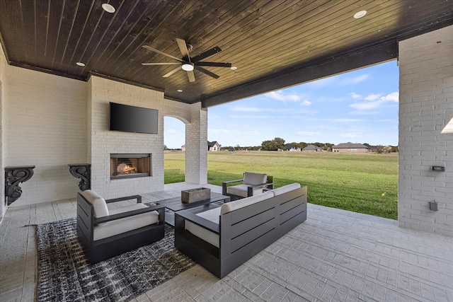 view of patio / terrace with ceiling fan and an outdoor living space with a fireplace