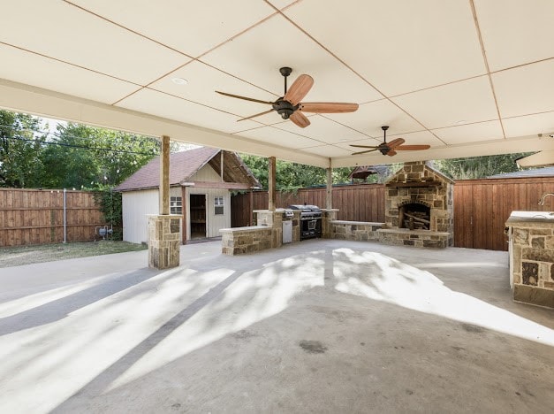 view of patio with an outdoor stone fireplace, a grill, and ceiling fan