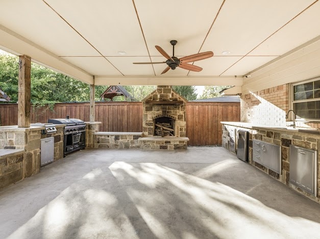 view of patio with an outdoor stone fireplace, an outdoor kitchen, and ceiling fan