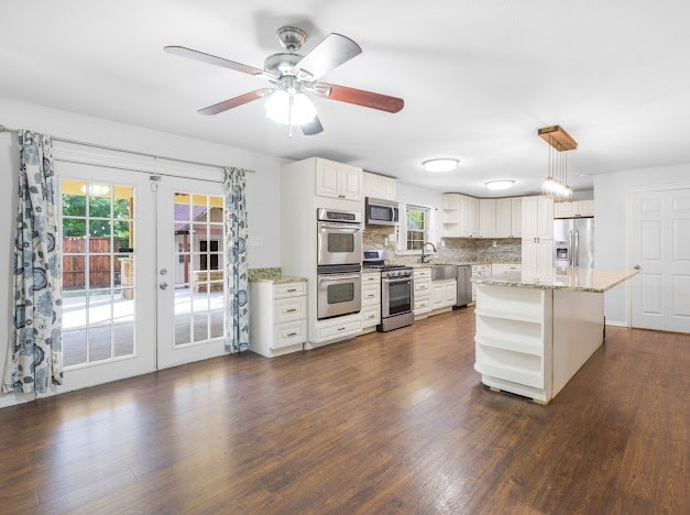 kitchen with a kitchen island, stainless steel appliances, dark wood-type flooring, french doors, and decorative light fixtures