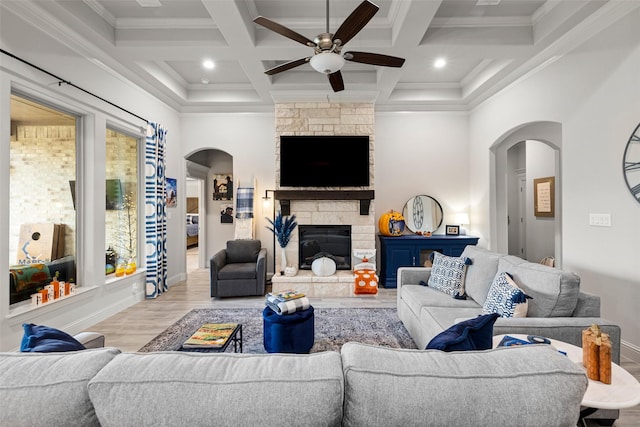 living room with coffered ceiling, a fireplace, light hardwood / wood-style floors, and beamed ceiling