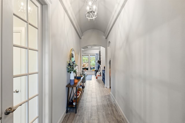 hall featuring crown molding, lofted ceiling, and a chandelier