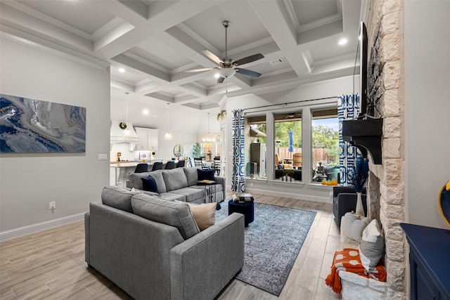 living room with ornamental molding, ceiling fan, beamed ceiling, and a fireplace