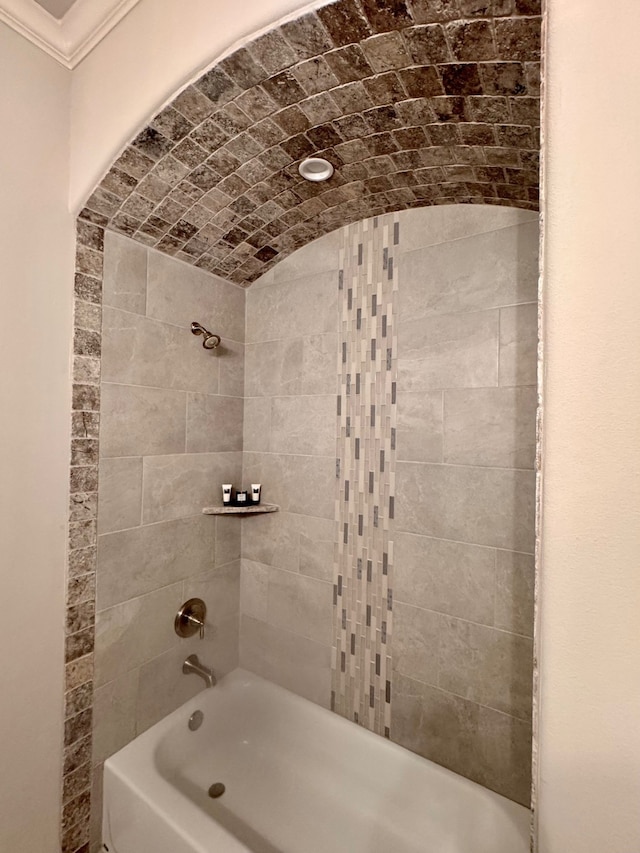 bathroom with lofted ceiling, tiled shower / bath combo, and brick ceiling