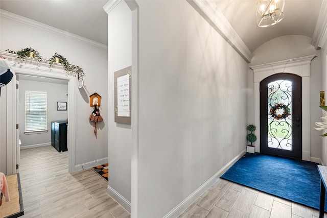 foyer entrance with lofted ceiling, a notable chandelier, crown molding, and light hardwood / wood-style flooring