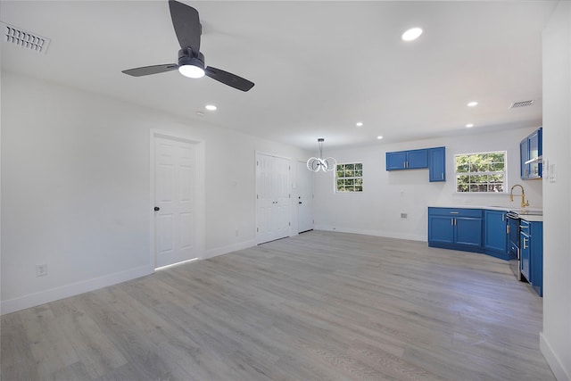 unfurnished living room with ceiling fan with notable chandelier, light hardwood / wood-style floors, and sink