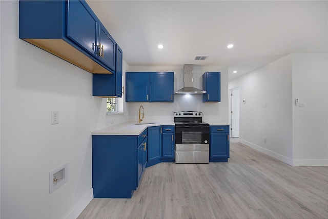 kitchen with blue cabinets, sink, wall chimney exhaust hood, stainless steel electric range oven, and light hardwood / wood-style floors