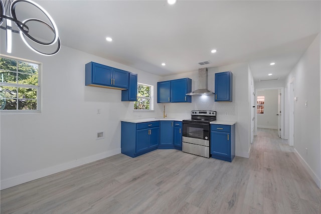 kitchen featuring electric range, wall chimney exhaust hood, light wood-type flooring, and a wealth of natural light