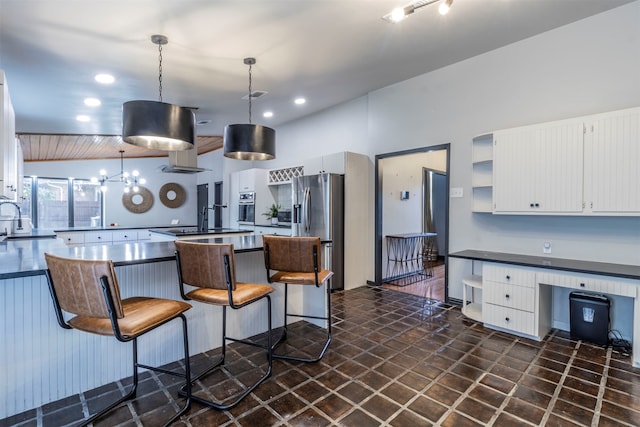 kitchen featuring vaulted ceiling, white cabinets, pendant lighting, and stainless steel appliances