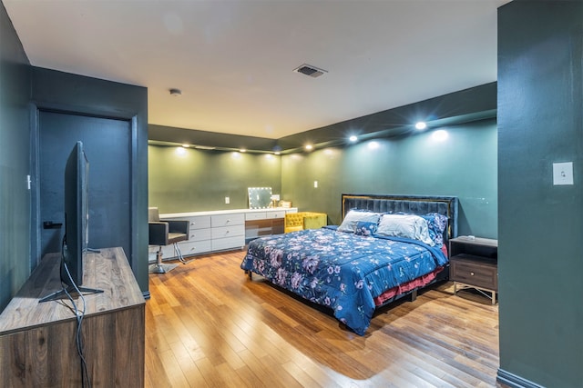 bedroom with built in desk and light wood-type flooring