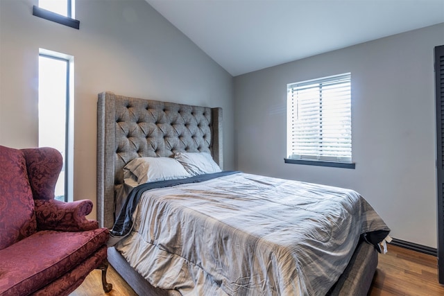 bedroom with multiple windows, hardwood / wood-style floors, and lofted ceiling