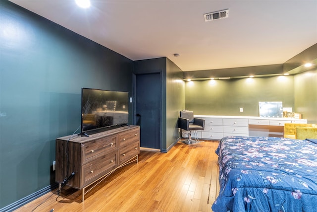 bedroom featuring built in desk and light wood-type flooring