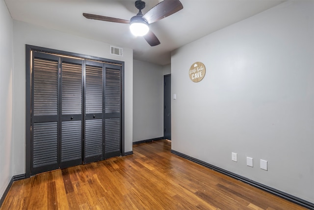 unfurnished bedroom featuring dark wood-type flooring, a closet, and ceiling fan