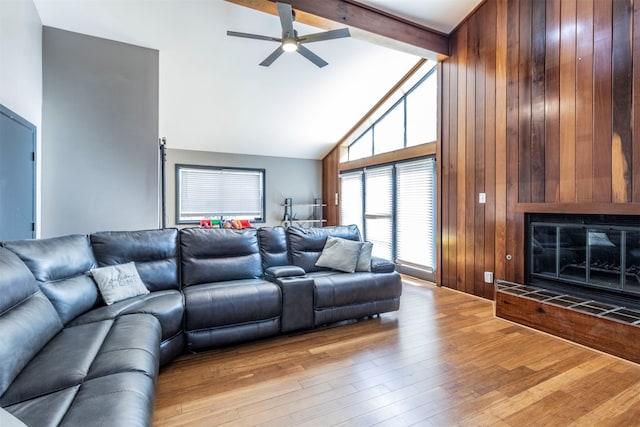 living room featuring beamed ceiling, a tile fireplace, light hardwood / wood-style flooring, and high vaulted ceiling