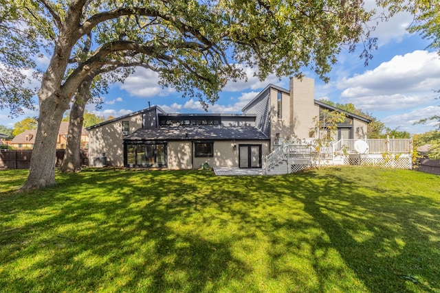 rear view of property featuring a wooden deck and a lawn