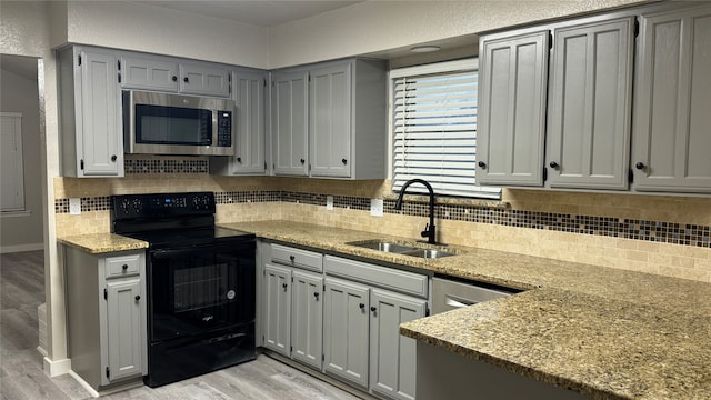 kitchen featuring decorative backsplash, black range with electric stovetop, sink, and light wood-type flooring