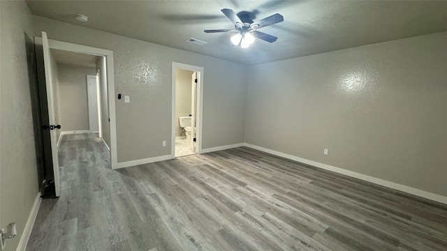 unfurnished bedroom featuring ceiling fan, light wood-type flooring, and ensuite bath