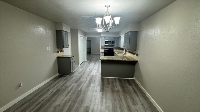 kitchen with black range with electric cooktop, sink, kitchen peninsula, and dark hardwood / wood-style floors