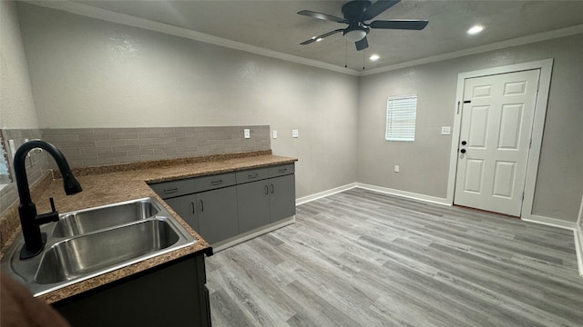 kitchen with ornamental molding, sink, tasteful backsplash, light wood-type flooring, and ceiling fan