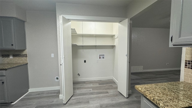 clothes washing area with light hardwood / wood-style floors, electric dryer hookup, washer hookup, and a tile fireplace