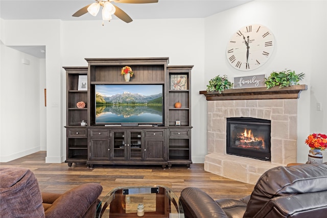 living room featuring dark wood-type flooring, a fireplace, and ceiling fan