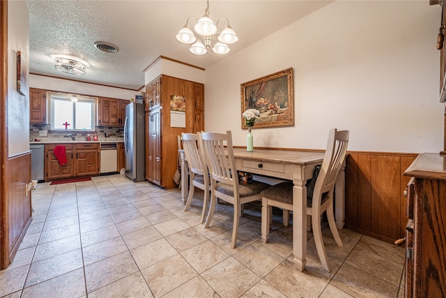 dining space with light tile patterned flooring, a textured ceiling, an inviting chandelier, and wooden walls