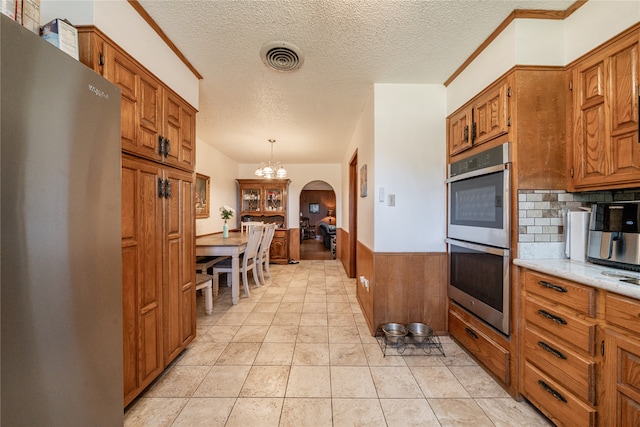 kitchen featuring appliances with stainless steel finishes, decorative backsplash, decorative light fixtures, and a textured ceiling