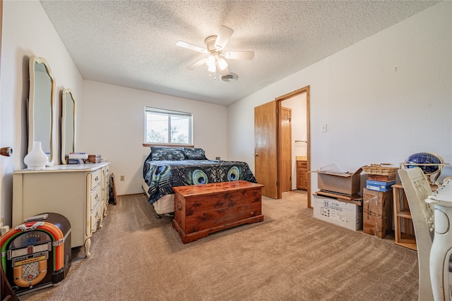 carpeted bedroom featuring a textured ceiling, ensuite bath, and ceiling fan