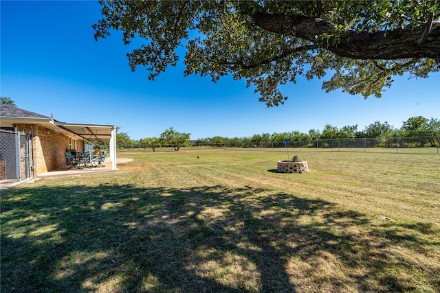 view of yard with a rural view, a patio area, and a fire pit