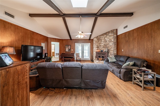 living room with french doors, lofted ceiling with beams, ceiling fan, light wood-type flooring, and wood walls