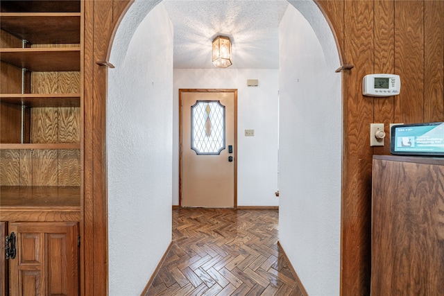 entryway featuring dark parquet flooring and a textured ceiling