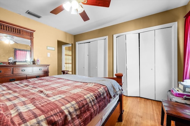 bedroom featuring two closets, light wood-type flooring, and ceiling fan