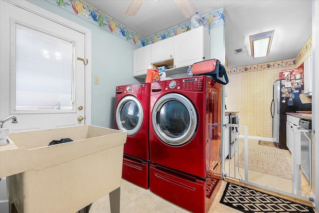 clothes washing area with sink, washer and clothes dryer, and cabinets