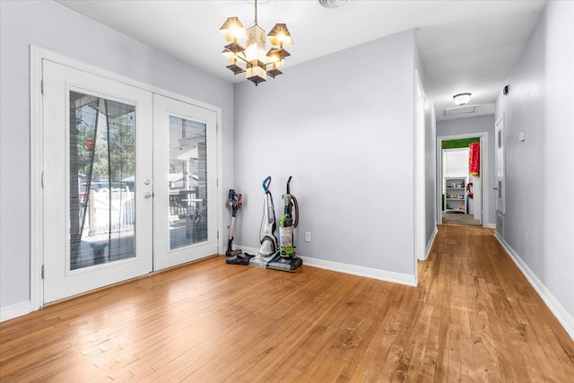 doorway to outside featuring a chandelier, light hardwood / wood-style flooring, and french doors