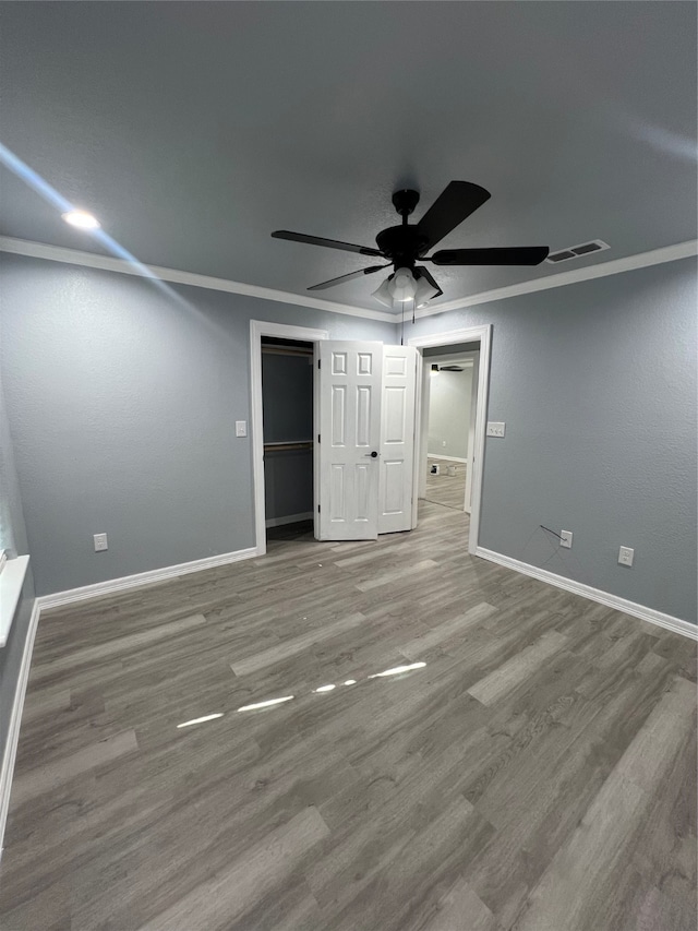 unfurnished bedroom featuring a closet, ceiling fan, crown molding, and wood-type flooring