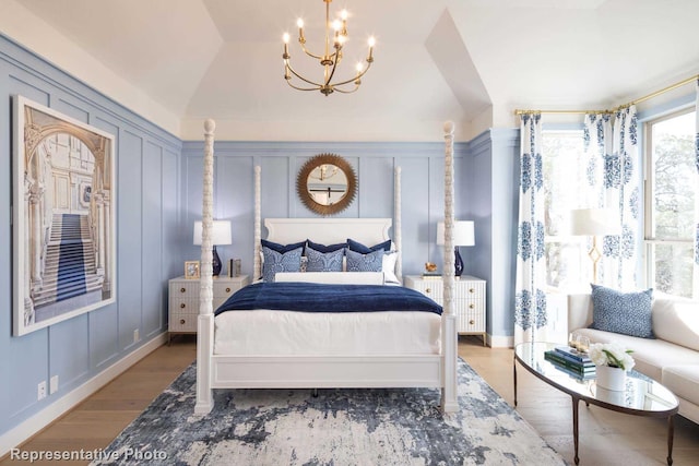 bedroom with a notable chandelier, wood-type flooring, and vaulted ceiling