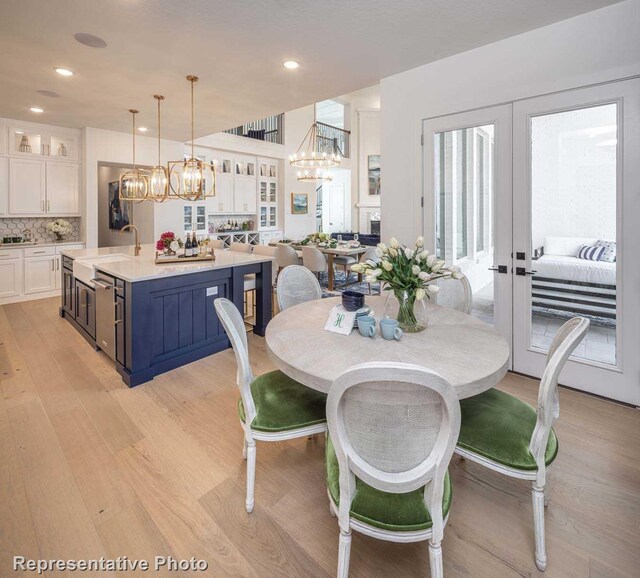 dining area featuring french doors, light wood-type flooring, a healthy amount of sunlight, and sink