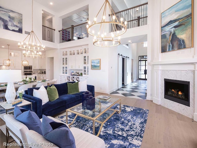 living room featuring a towering ceiling, a barn door, hardwood / wood-style flooring, and a tiled fireplace