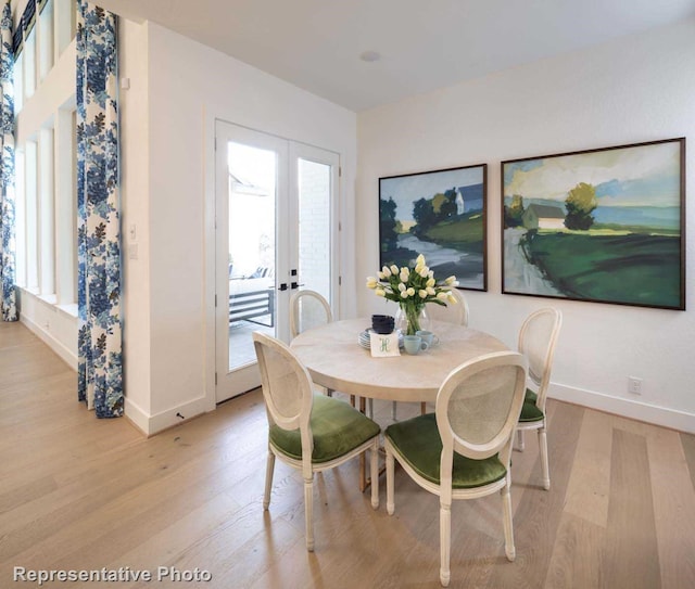 dining room with light hardwood / wood-style flooring, a wealth of natural light, and french doors