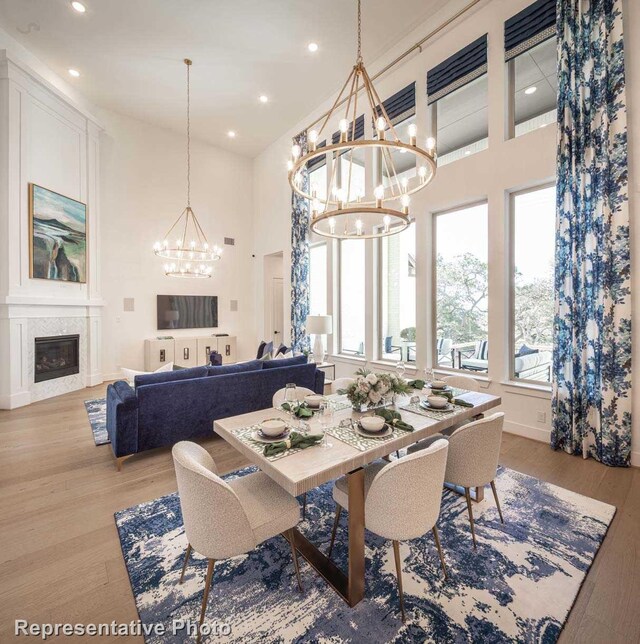 dining room with a chandelier, wood-type flooring, and a towering ceiling