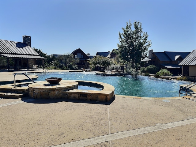 view of swimming pool featuring an in ground hot tub and pool water feature