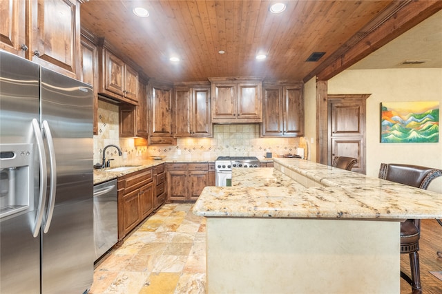 kitchen featuring a kitchen island, a kitchen breakfast bar, stainless steel appliances, sink, and light stone countertops